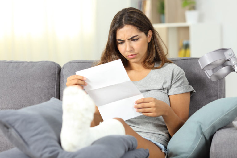 Woman in foot cast reading bill