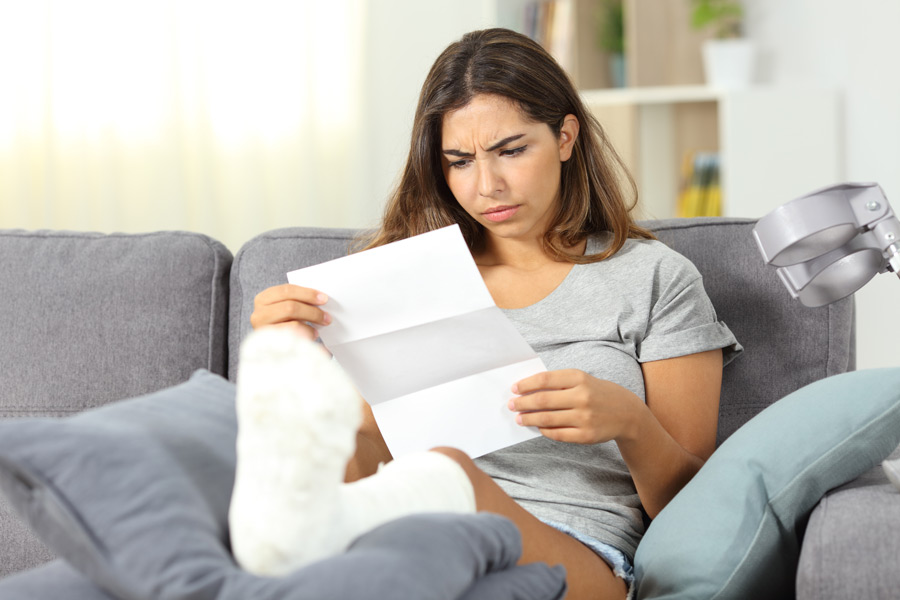 Woman in foot cast reading bill