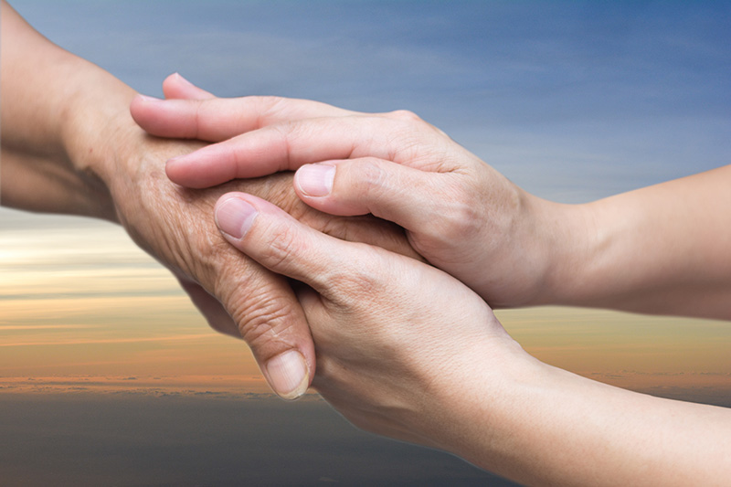 Caregiver hand holding elder hand