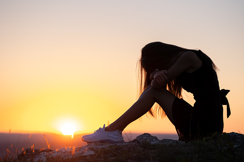 silhouette of upset woman with sunset in background
