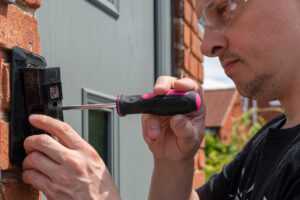 Man installing a smart doorbell with security camera and solar c