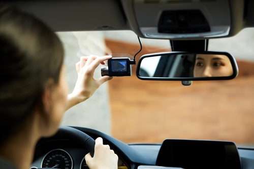 Driver adjusts dashboard camera near rearview mirror inside vehicle